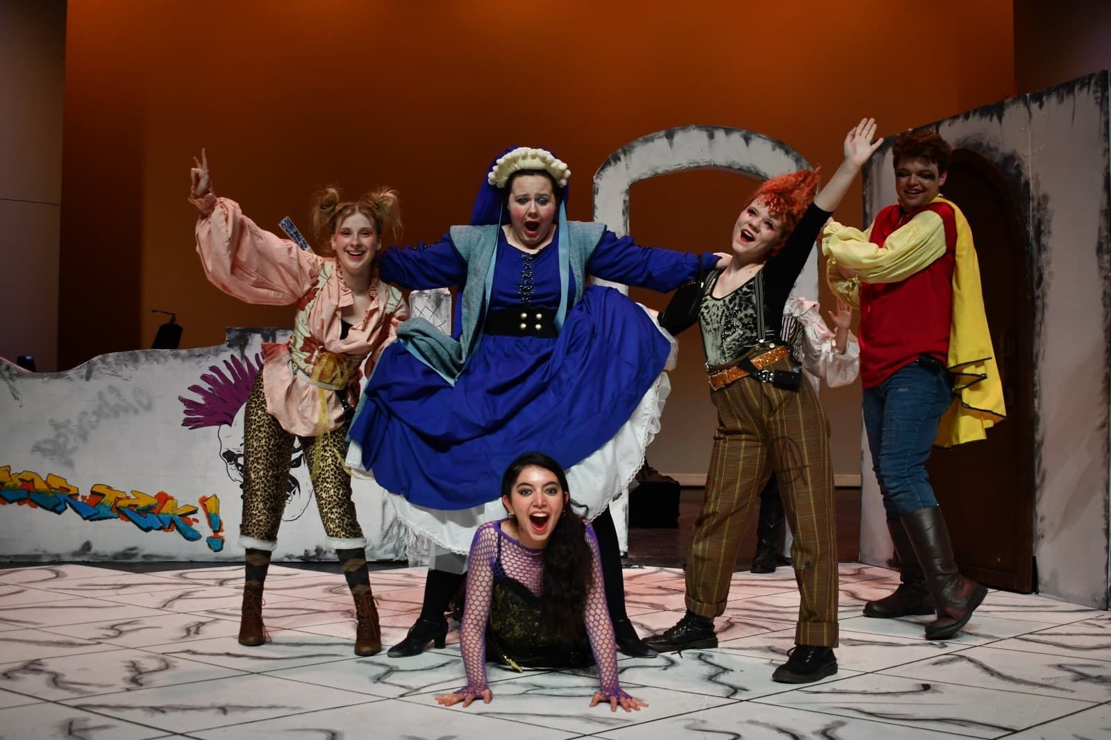 Students performing a dramatic scene under stage lighting