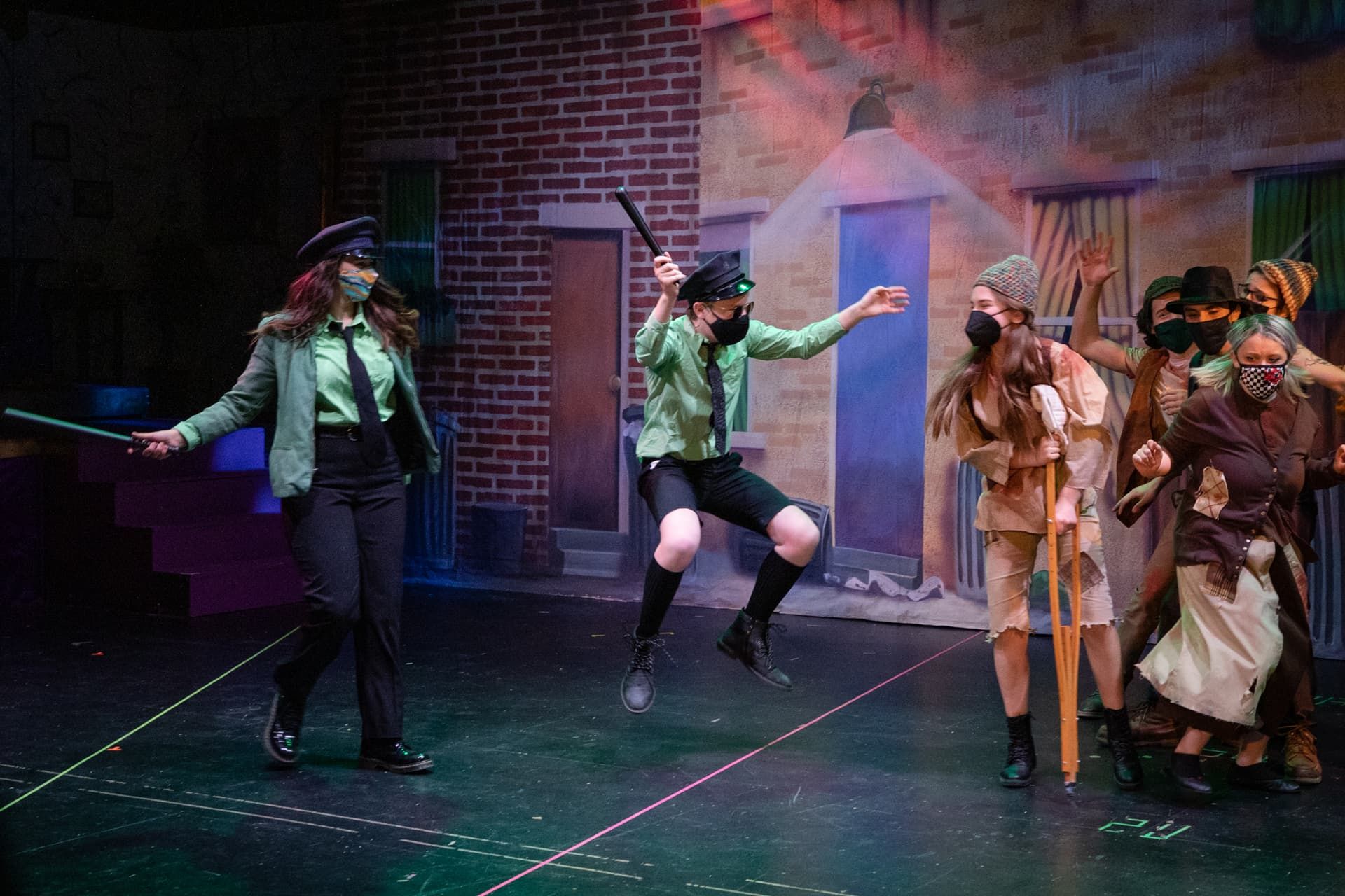 Students leaping over barrels in an ensemble number from Urinetown
