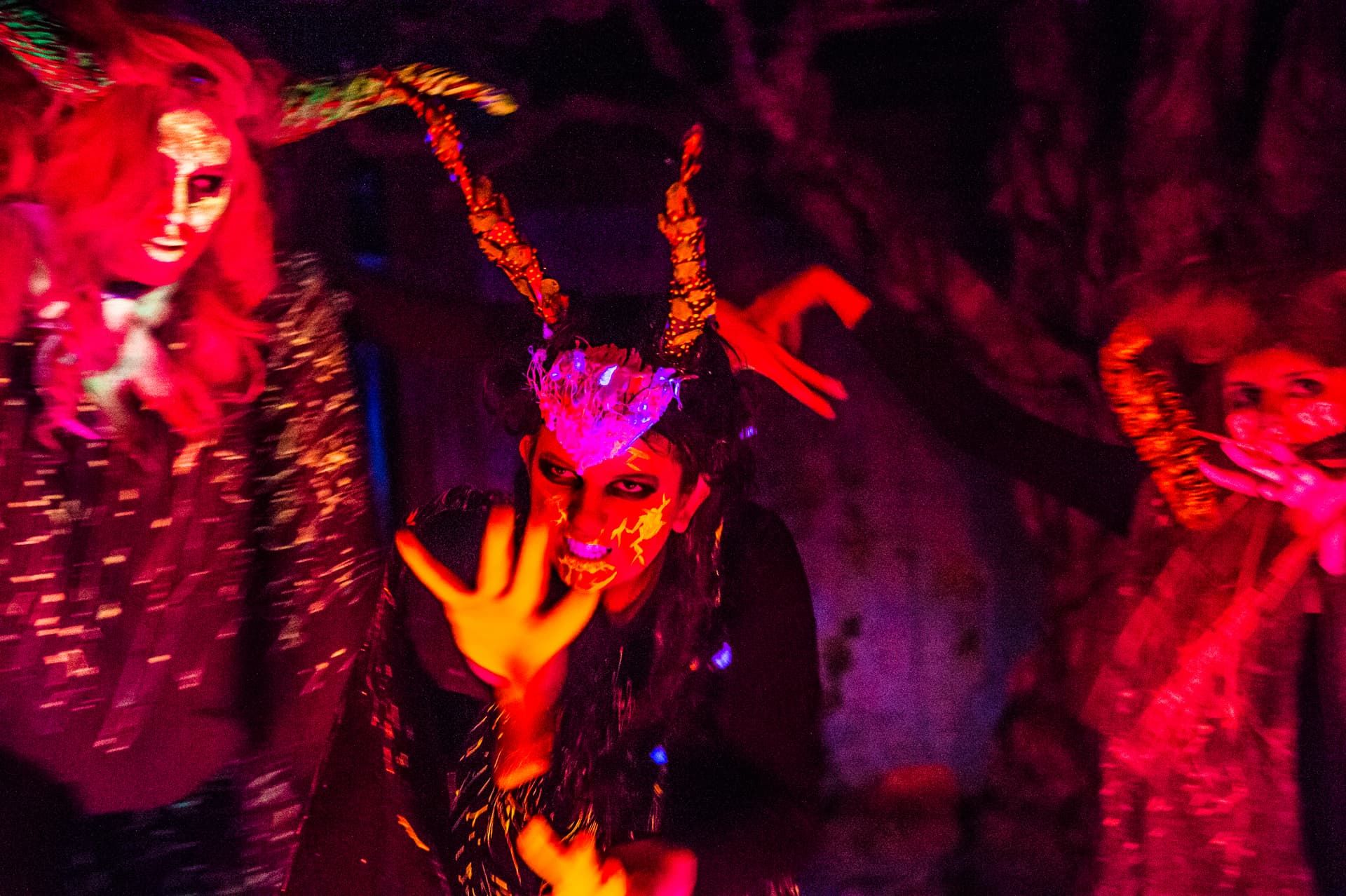 The witches conjure under blood-red light in Macbeth